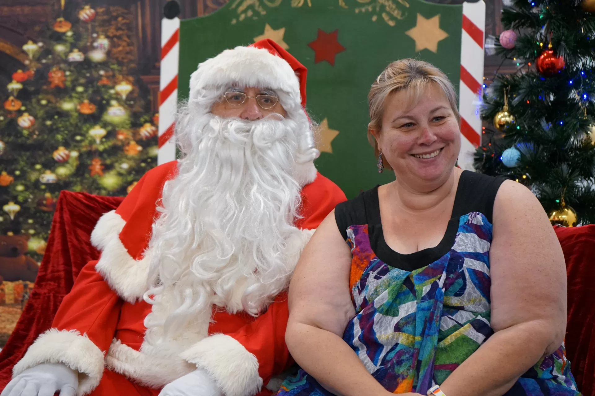 A woman smiles sitting on the right of Santa