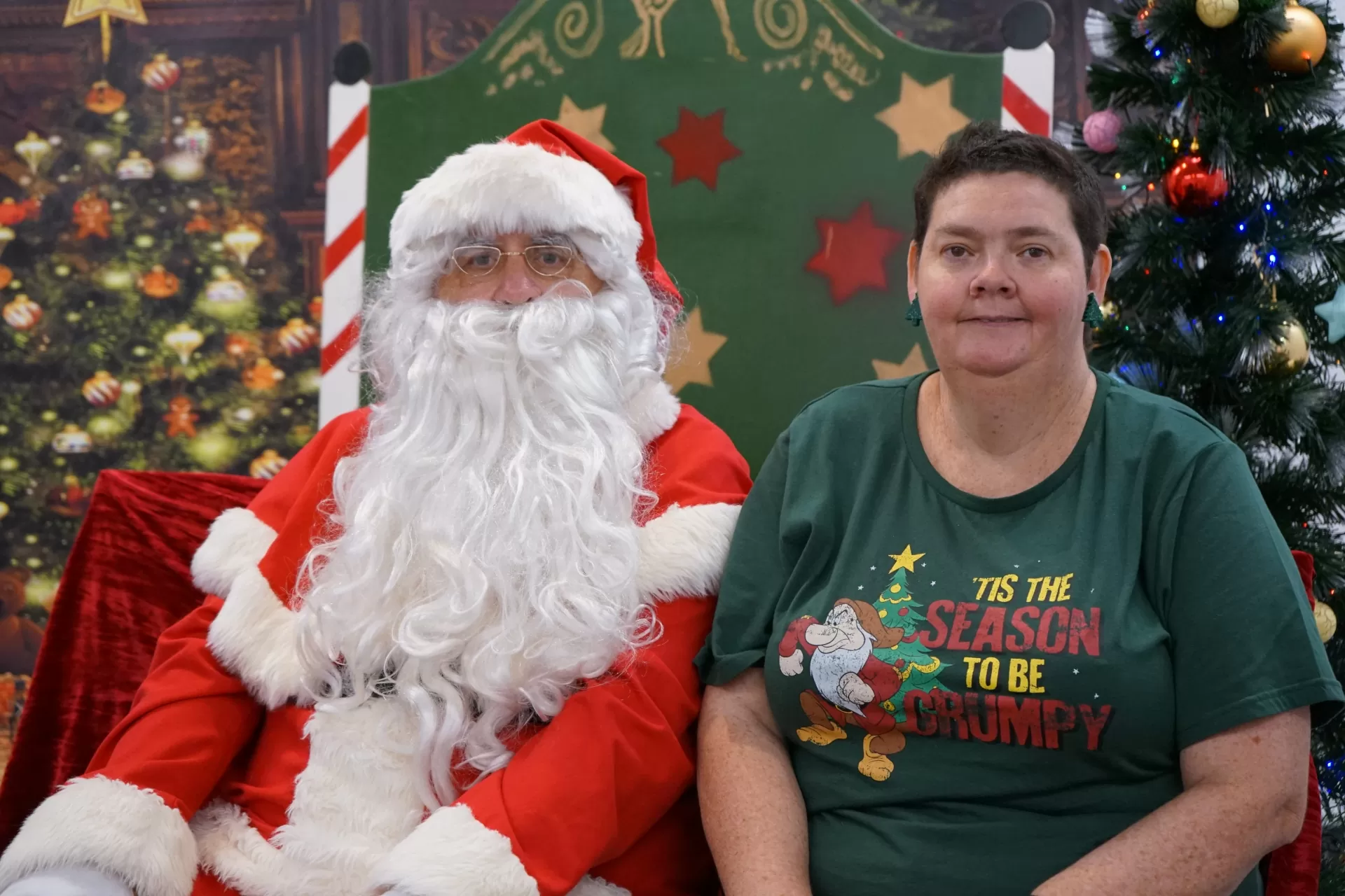 A woman in a green shirt sits on Santa's right