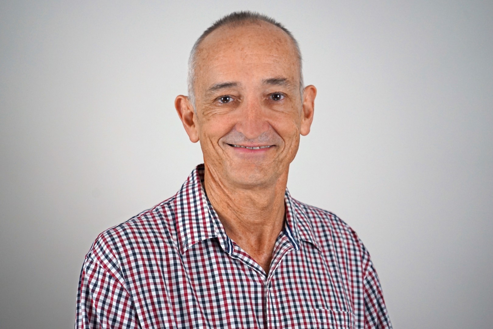 A photo of board member David looking at the camera smiling on a grey background