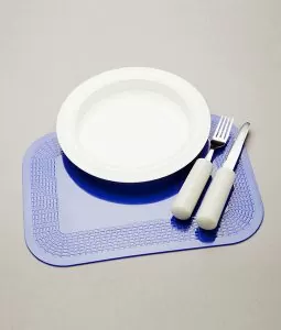 A bowl, spoon and fork sitting on a blue mat