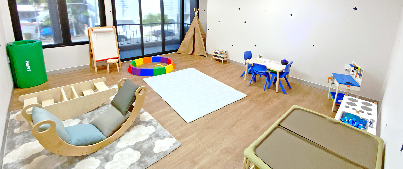 An Allied Health room with toys, activity stations, rugs, slides and play equipment.