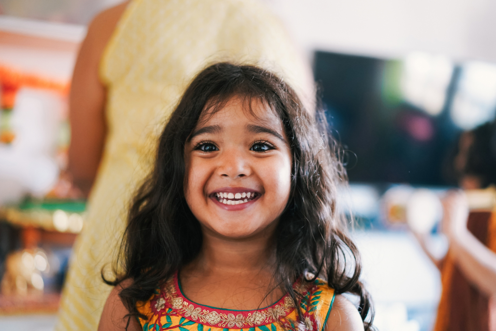 A young girl smiles widely at the camera