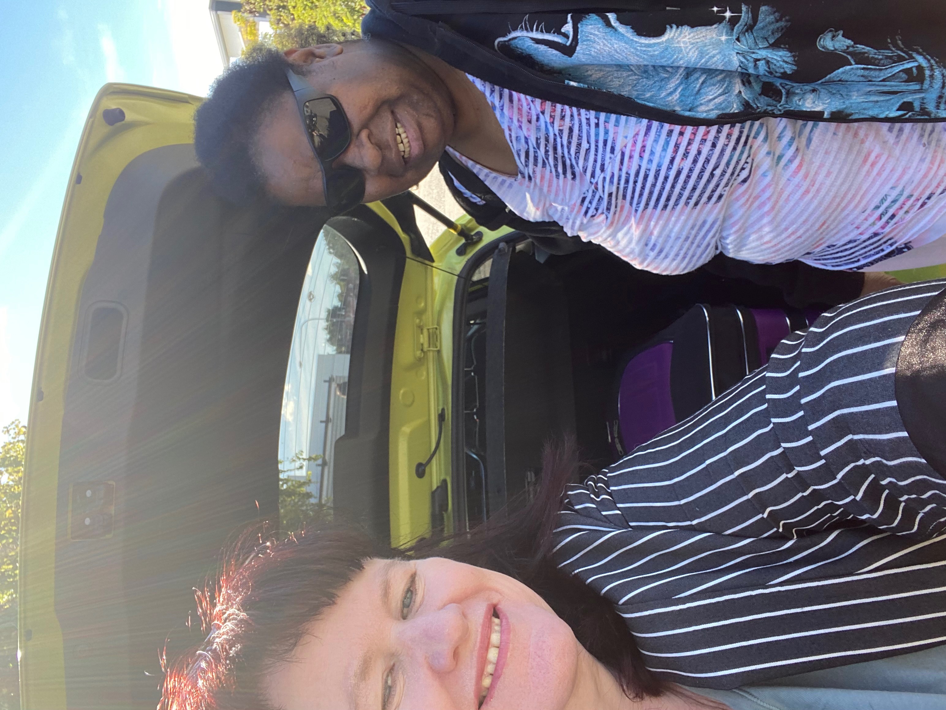Taum and her support worker standing in front of the open boot of a yellow car