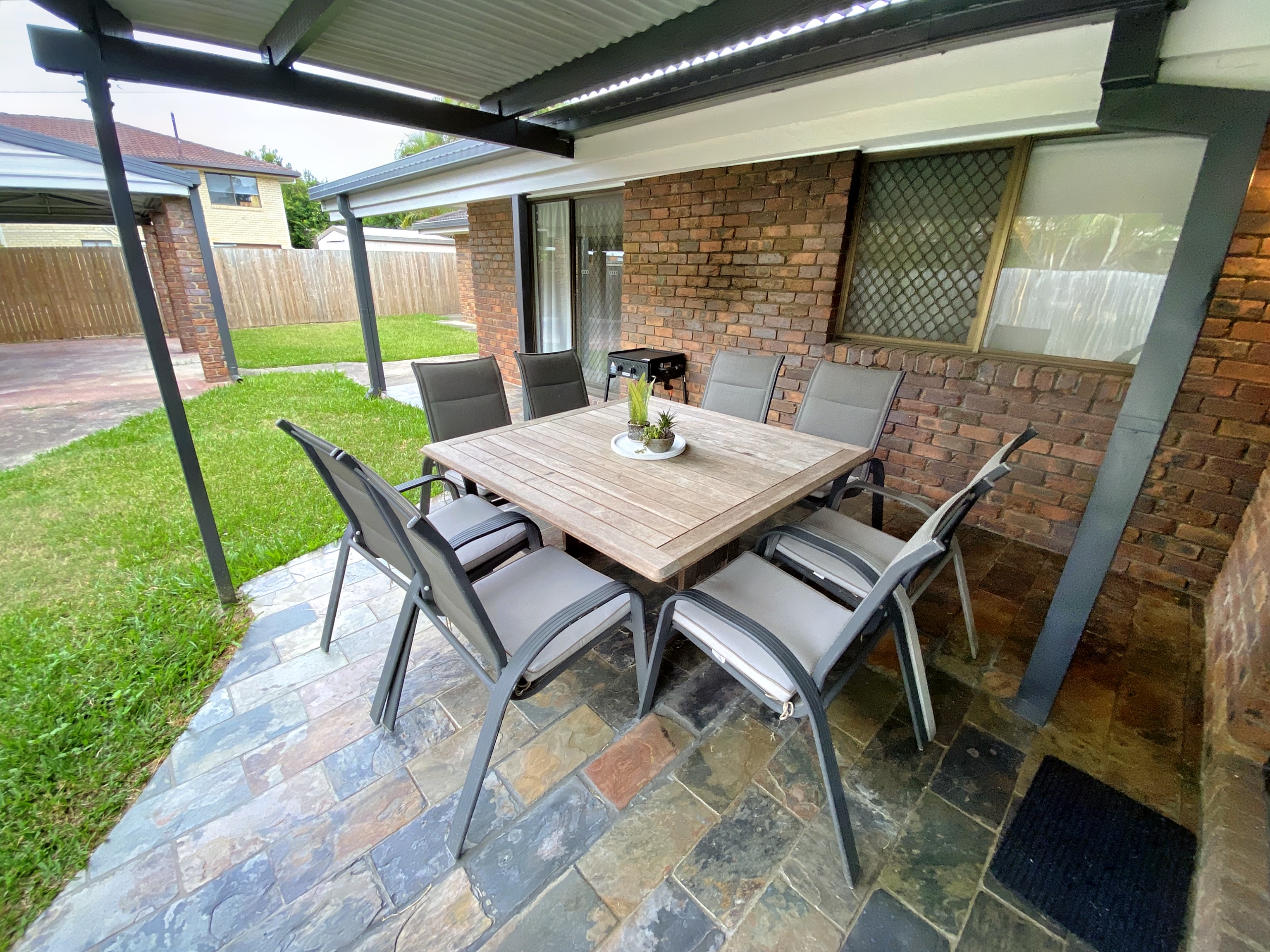 Covered outdoor patio with 8-seater dining set and BBQ