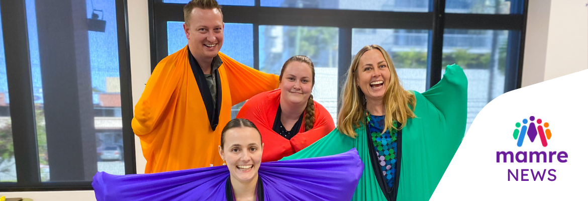 Four people standing in brightly coloured sensory body socks smiling