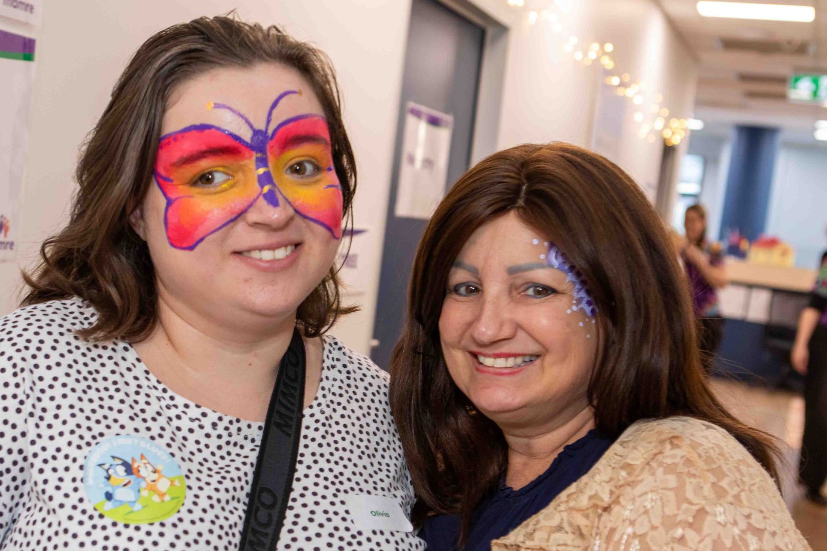 Two women with painted faces smile at the camera.